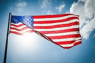 United States of America Flag with clouds and the sun shining through it