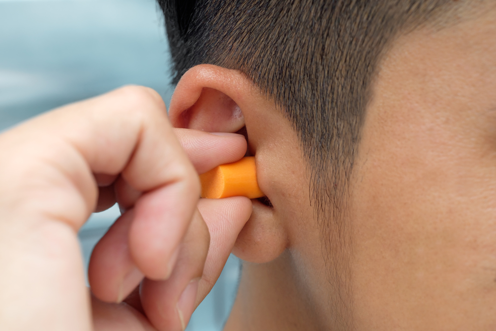 Man putting in ear plugs.